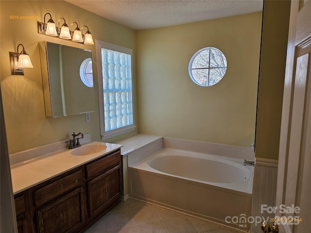 bathroom featuring a garden tub, tile patterned flooring, a textured ceiling, and vanity