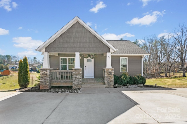 craftsman inspired home featuring covered porch and a shingled roof