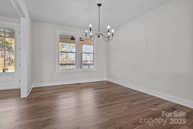 unfurnished dining area featuring dark wood-type flooring, a wealth of natural light, and a notable chandelier