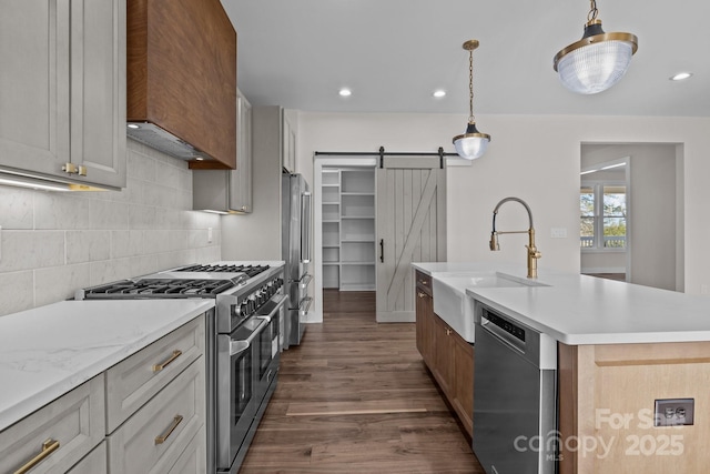 kitchen with pendant lighting, a center island with sink, a barn door, a sink, and high quality appliances