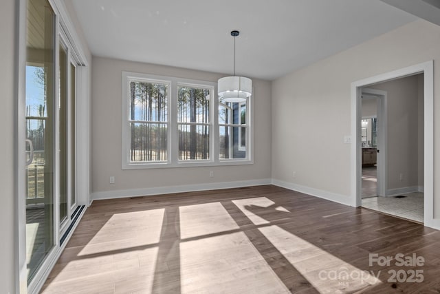 unfurnished dining area featuring visible vents, dark wood finished floors, and baseboards