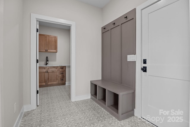 mudroom featuring baseboards and a sink