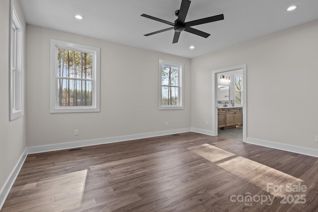 unfurnished bedroom featuring ensuite bathroom, recessed lighting, dark wood-style flooring, a ceiling fan, and baseboards