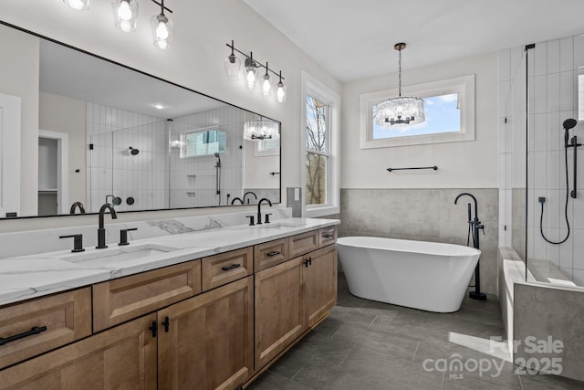 bathroom featuring a notable chandelier, a sink, a freestanding bath, a shower stall, and double vanity