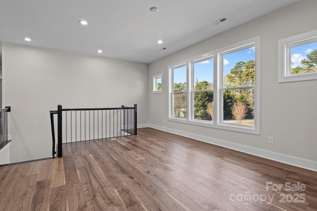 unfurnished room featuring baseboards, visible vents, wood finished floors, and recessed lighting