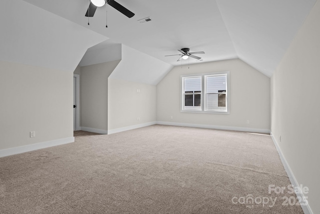 additional living space featuring vaulted ceiling, light carpet, visible vents, and baseboards