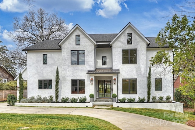 view of front of house with a front lawn, fence, brick siding, and a shingled roof