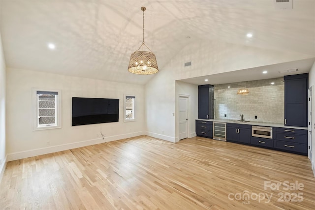 unfurnished living room with wine cooler, light wood-type flooring, a sink, and visible vents