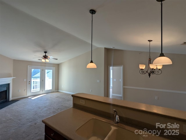 kitchen featuring open floor plan, hanging light fixtures, carpet, and a sink