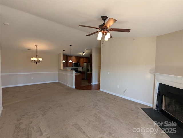 unfurnished living room featuring a fireplace with flush hearth, dark carpet, baseboards, and ceiling fan with notable chandelier