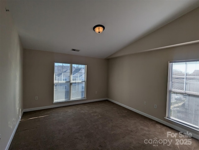 unfurnished room with lofted ceiling, baseboards, visible vents, and dark carpet