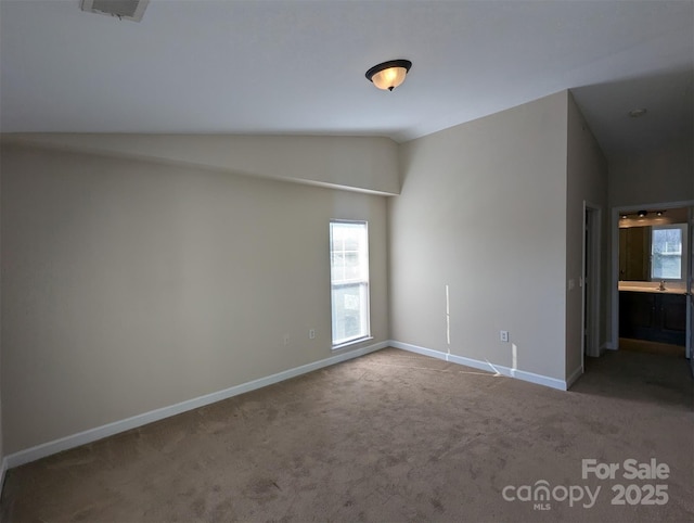 empty room featuring lofted ceiling, carpet flooring, visible vents, and baseboards