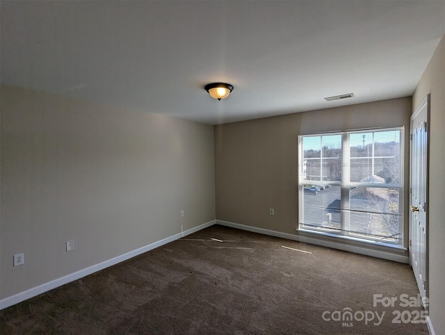 empty room featuring dark carpet and baseboards