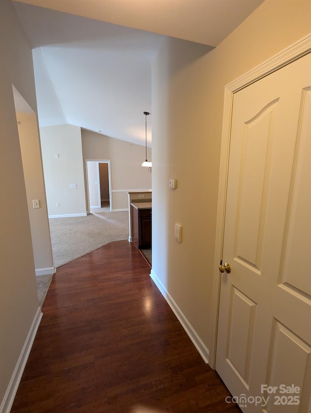 hallway with lofted ceiling, dark wood-style flooring, and baseboards