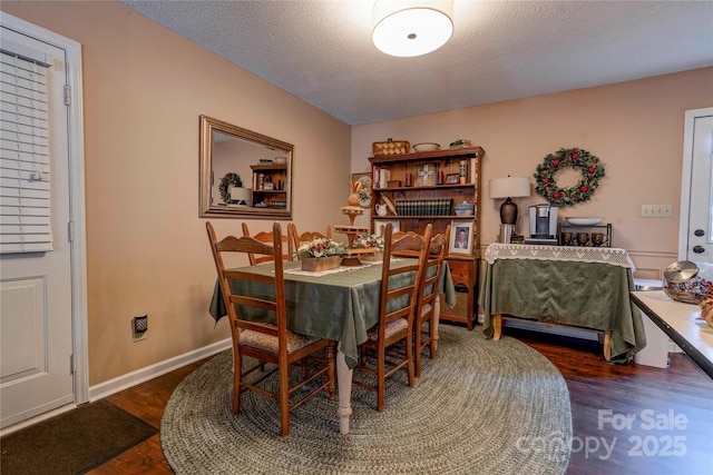 dining space featuring baseboards, dark wood finished floors, and a textured ceiling