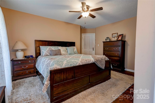 bedroom with a textured ceiling, baseboards, and a ceiling fan