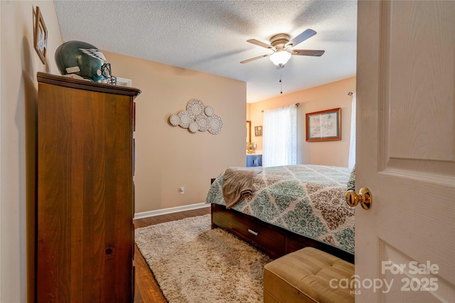 bedroom with baseboards, a ceiling fan, a textured ceiling, and wood finished floors