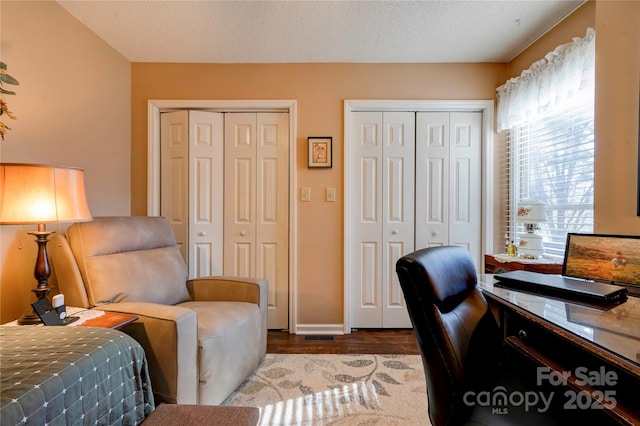 office area with a textured ceiling, baseboards, and wood finished floors