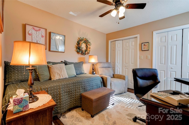 bedroom with a ceiling fan and two closets