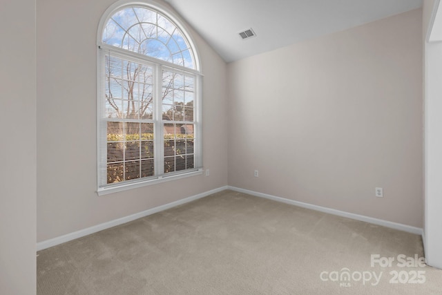 empty room with light carpet, lofted ceiling, visible vents, and baseboards