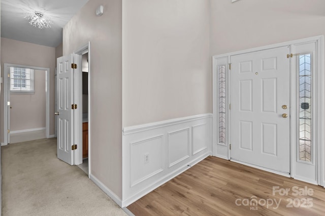 entryway with light wood-type flooring, a wainscoted wall, and a decorative wall