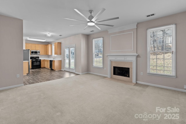 unfurnished living room with visible vents, baseboards, ceiling fan, carpet, and a fireplace