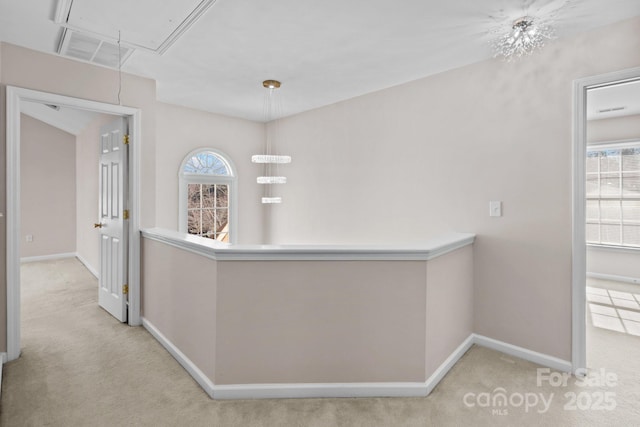 hallway with baseboards, carpet flooring, attic access, and a healthy amount of sunlight