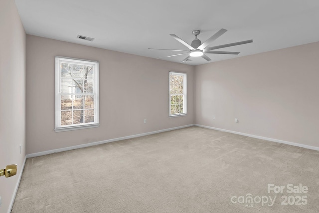 spare room featuring ceiling fan, visible vents, baseboards, and light colored carpet