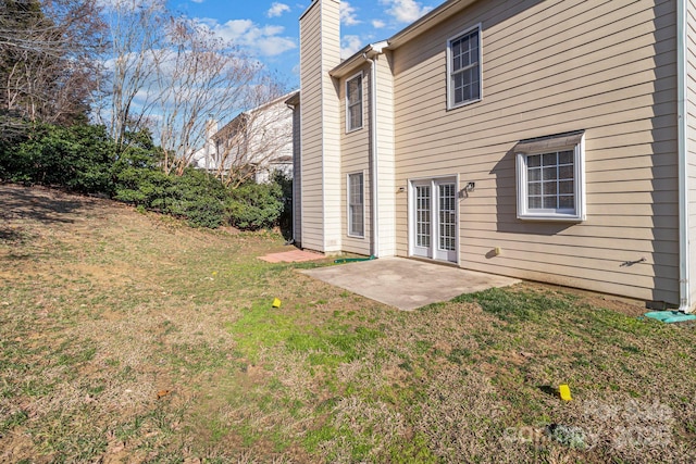 back of property featuring a patio area, a lawn, and a chimney