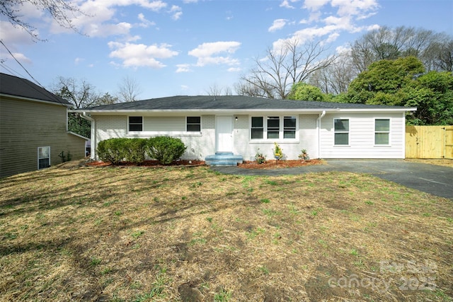 single story home with brick siding, fence, and a front lawn