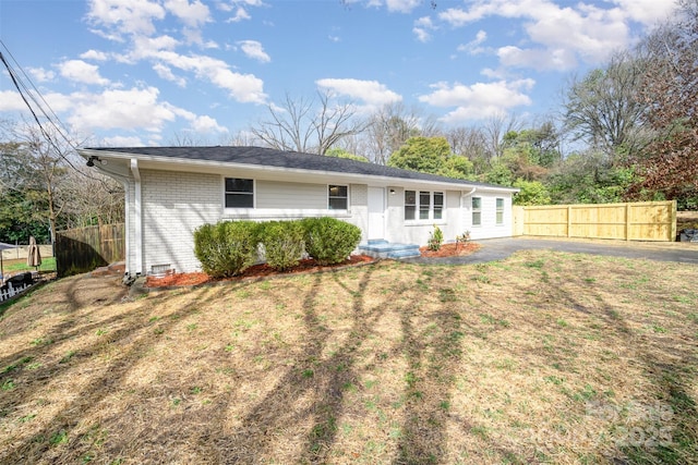 view of front of property featuring brick siding, a front lawn, and fence