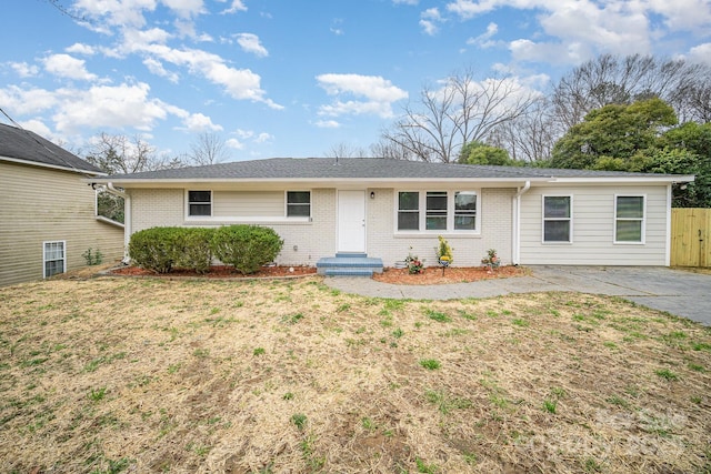 ranch-style home with a front yard, brick siding, and fence