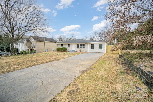 single story home featuring driveway, fence, and a front lawn