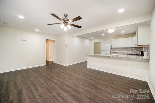 kitchen featuring a peninsula, visible vents, freestanding refrigerator, dark wood-style floors, and tasteful backsplash