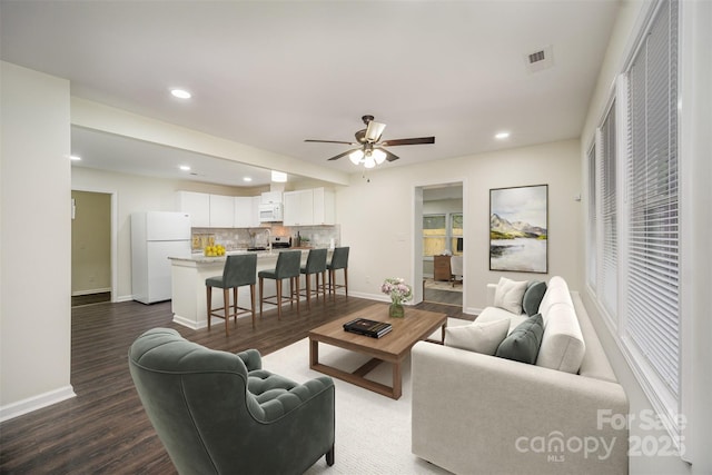 living area with baseboards, visible vents, dark wood-type flooring, and recessed lighting