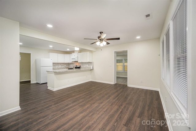 unfurnished living room with baseboards, visible vents, and dark wood finished floors