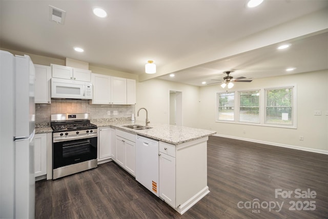 kitchen with tasteful backsplash, visible vents, a sink, white appliances, and a peninsula