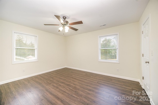 unfurnished room with baseboards, visible vents, ceiling fan, and dark wood-style flooring