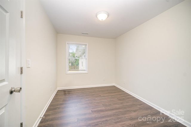 unfurnished room featuring visible vents, baseboards, and dark wood-style flooring