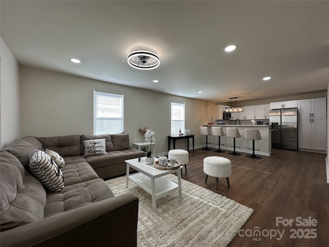 living area featuring baseboards, dark wood finished floors, and recessed lighting