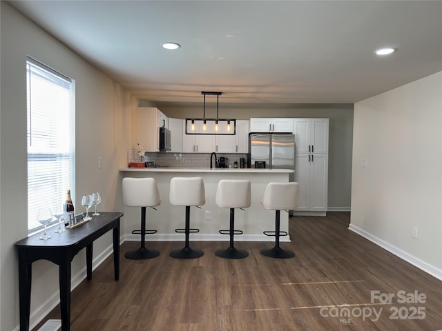 kitchen featuring stainless steel appliances, tasteful backsplash, white cabinets, a sink, and a peninsula