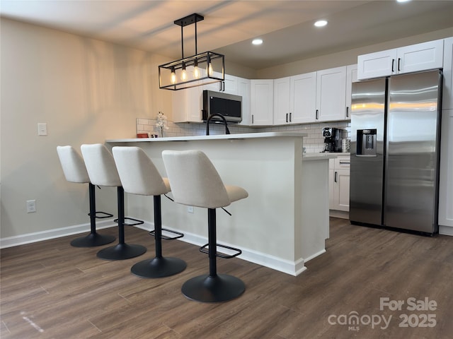 kitchen featuring a peninsula, white cabinetry, stainless steel appliances, and dark wood-type flooring