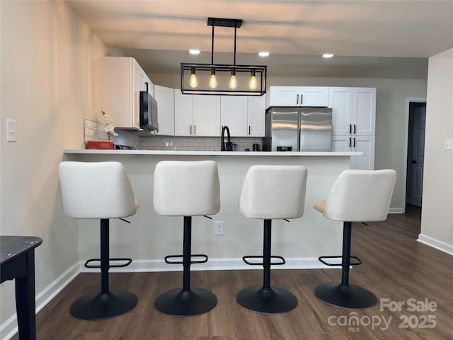 kitchen featuring decorative backsplash, a breakfast bar, white cabinetry, and stainless steel fridge with ice dispenser