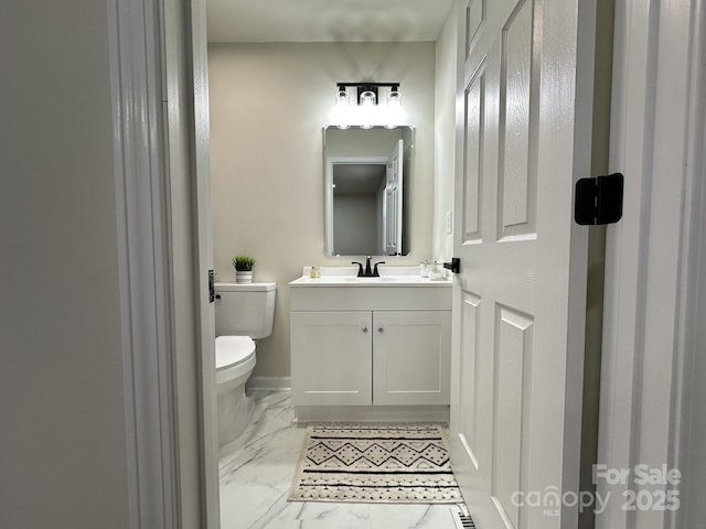 half bathroom featuring marble finish floor, vanity, and toilet