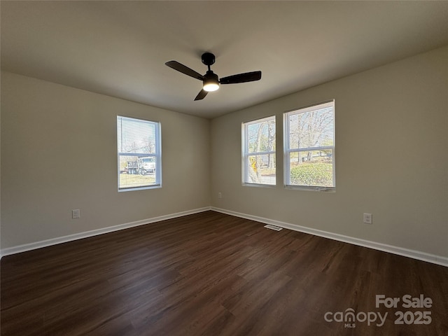 empty room featuring ceiling fan, dark wood-type flooring, visible vents, and baseboards