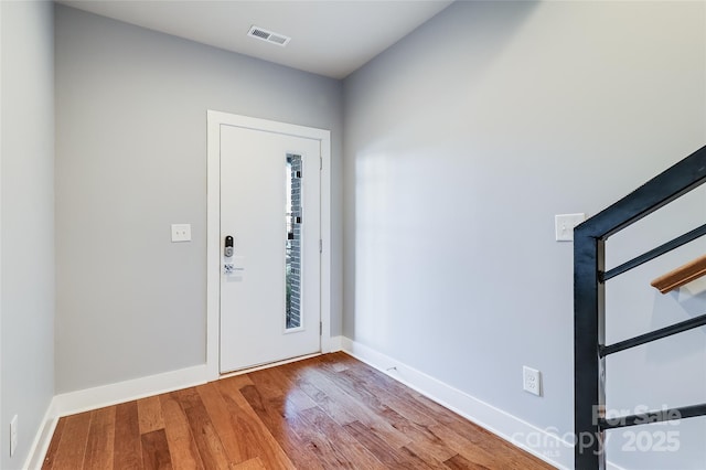 foyer entrance featuring visible vents, baseboards, and wood finished floors