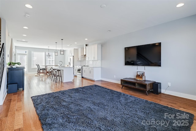 living room with light wood-type flooring, baseboards, and recessed lighting