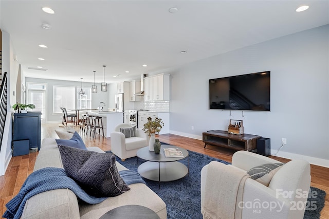 living area featuring light wood finished floors, baseboards, and recessed lighting