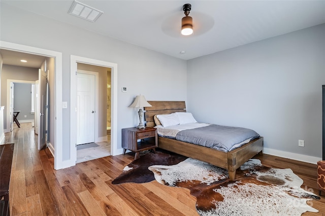 bedroom featuring visible vents, ceiling fan, baseboards, and wood finished floors