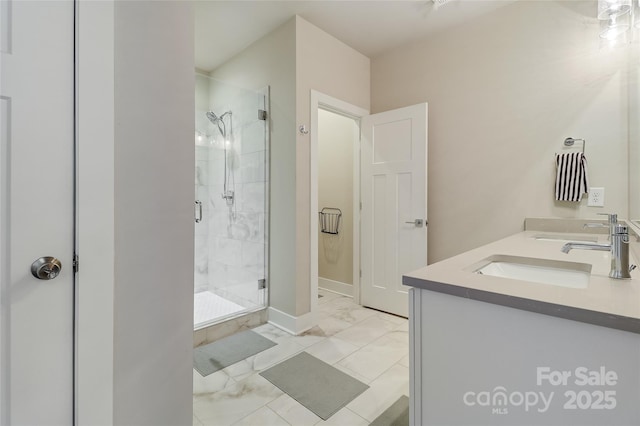 bathroom with marble finish floor, double vanity, a stall shower, a sink, and baseboards